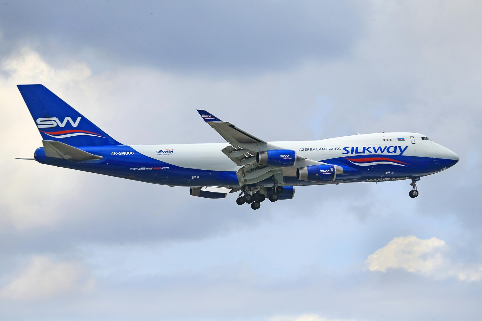 Silk Way cargo aircraft flying amidst a partly cloudy sky, showcasing modern aviation.